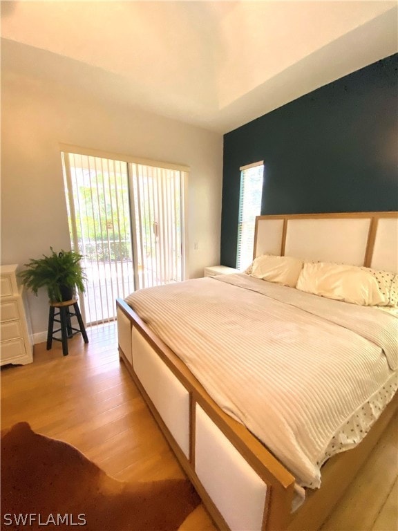 bedroom featuring wood-type flooring, access to exterior, and multiple windows