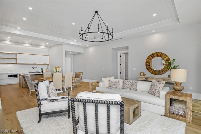 living room with light wood-type flooring, a tray ceiling, an inviting chandelier, and wood ceiling