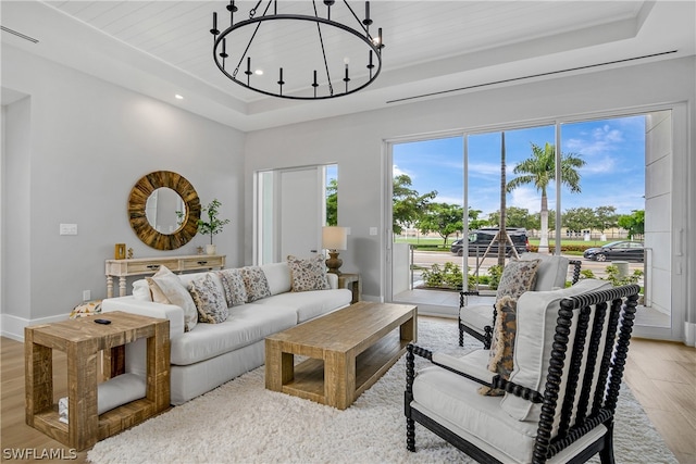 living room featuring a tray ceiling, an inviting chandelier, wooden ceiling, and light hardwood / wood-style floors