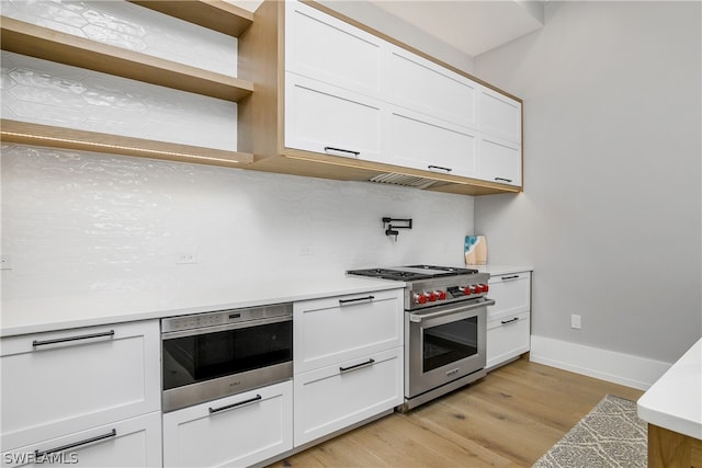 kitchen featuring backsplash, white cabinetry, designer stove, and light wood-type flooring