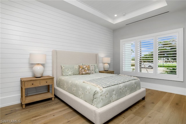 bedroom featuring light hardwood / wood-style flooring and a raised ceiling