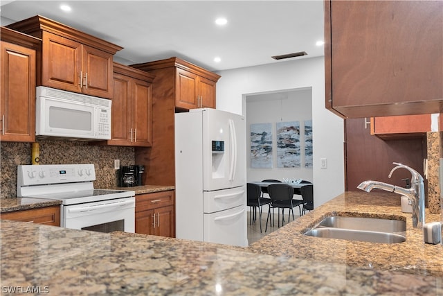 kitchen featuring sink, decorative backsplash, light stone counters, and white appliances