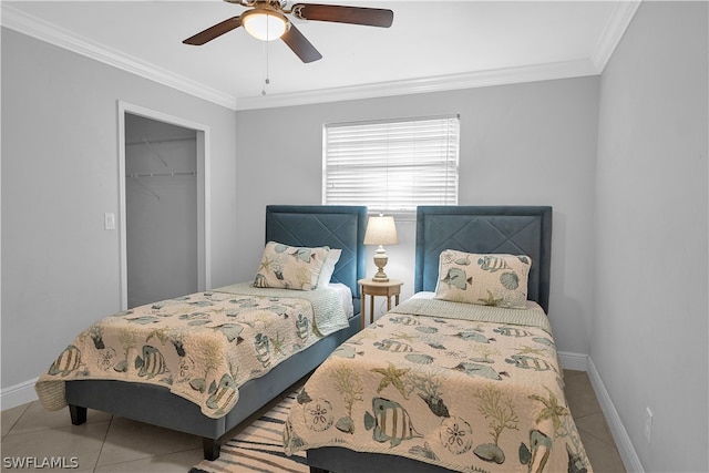 tiled bedroom with a spacious closet, ceiling fan, crown molding, and a closet