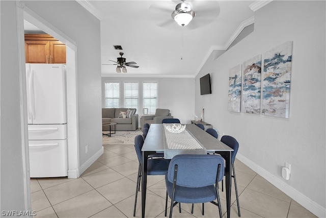 tiled dining space featuring vaulted ceiling, crown molding, and ceiling fan