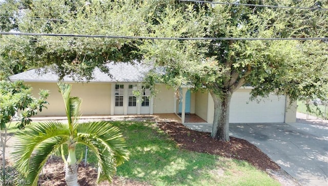 view of front of property with driveway, roof with shingles, french doors, and stucco siding