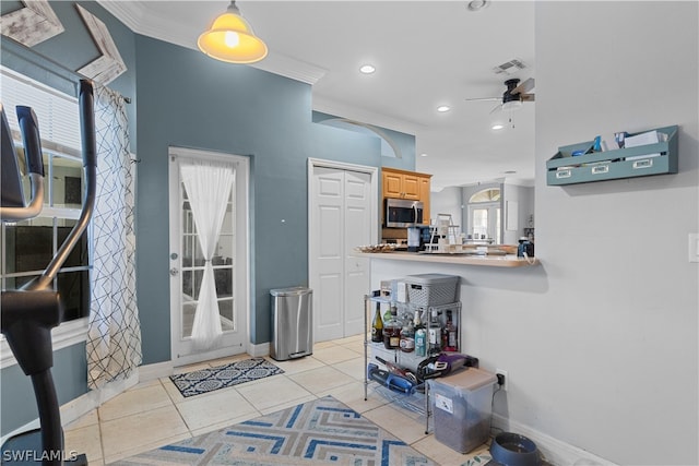 tiled entrance foyer featuring ceiling fan, plenty of natural light, and crown molding