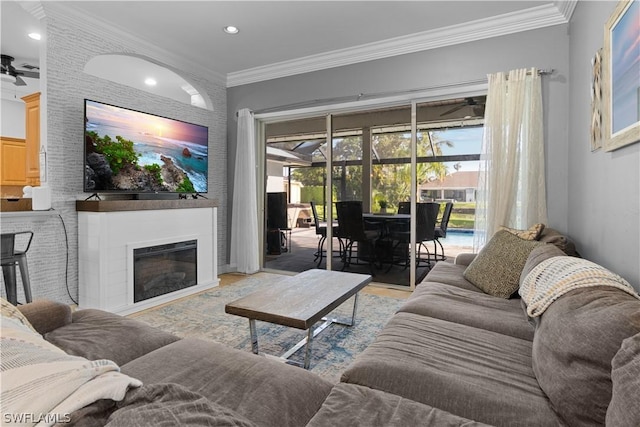 living room featuring ceiling fan, ornamental molding, and a fireplace