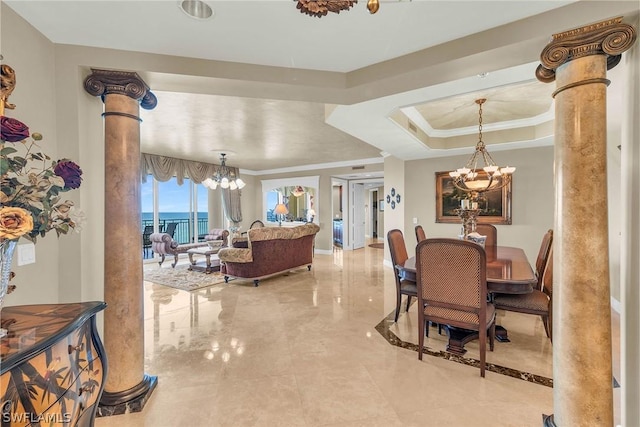 dining room with decorative columns, ornamental molding, a notable chandelier, a raised ceiling, and a water view