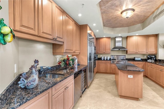 kitchen featuring wall chimney exhaust hood, range, a center island, dark stone countertops, and stainless steel dishwasher