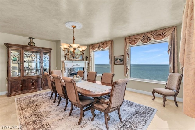 dining area with an inviting chandelier, a fireplace, a wealth of natural light, and a water view