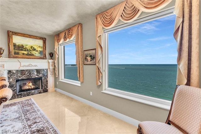 sitting room featuring a water view, a fireplace, and a wealth of natural light