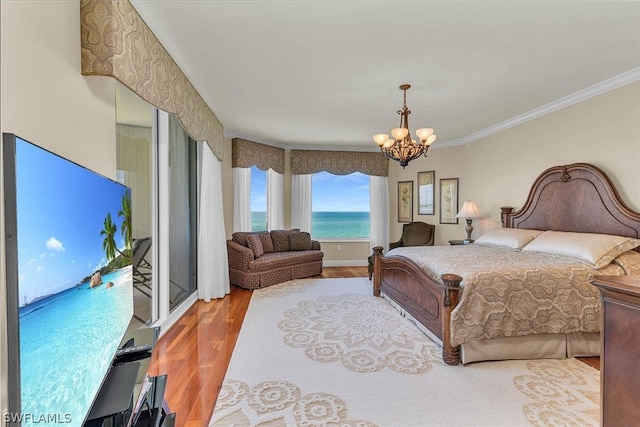 bedroom with ornamental molding, a water view, hardwood / wood-style floors, and a chandelier