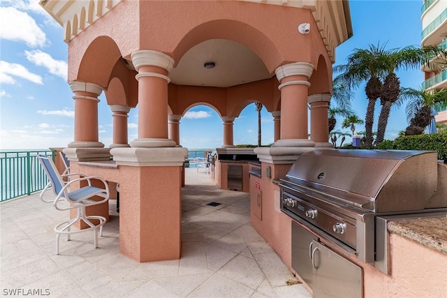 view of patio / terrace featuring a water view, area for grilling, and exterior bar