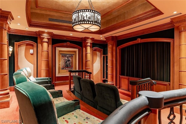 carpeted cinema room with decorative columns, crown molding, and a tray ceiling