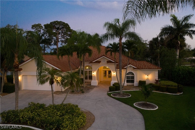 mediterranean / spanish home with a garage, a front yard, concrete driveway, and stucco siding