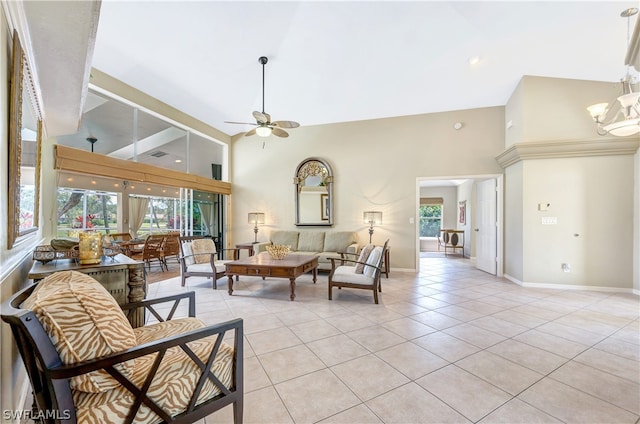 living area with light tile patterned floors, high vaulted ceiling, ceiling fan with notable chandelier, and baseboards