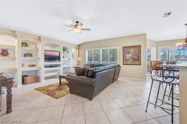 living area with light tile patterned floors, plenty of natural light, built in features, and ceiling fan with notable chandelier