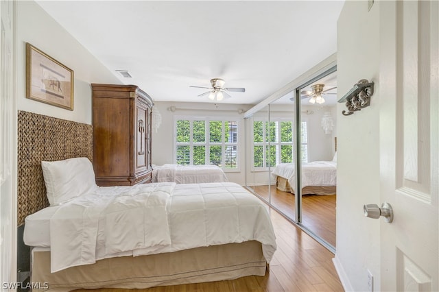 bedroom with light wood-type flooring, ceiling fan, and visible vents