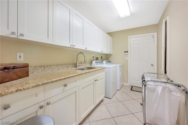 clothes washing area with light tile patterned floors, washing machine and dryer, a sink, and cabinet space