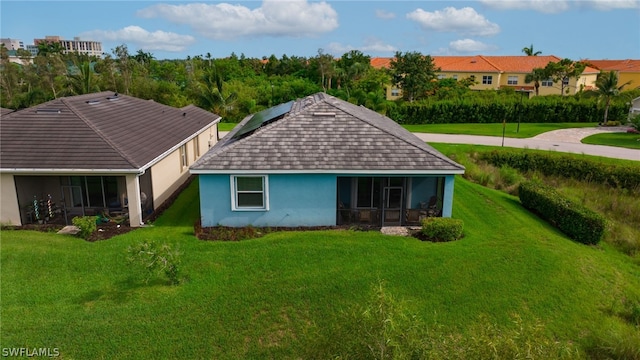 back of property featuring solar panels, a sunroom, and a yard