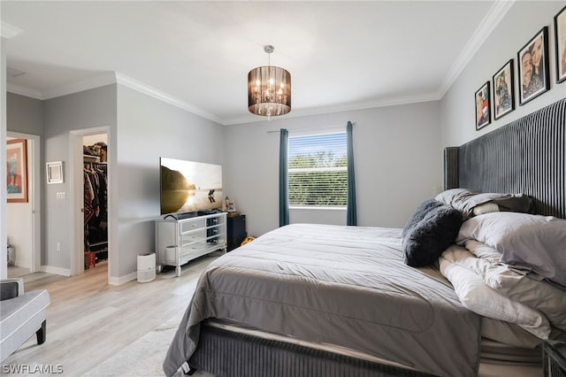 bedroom with a notable chandelier, a closet, light hardwood / wood-style floors, a walk in closet, and ornamental molding