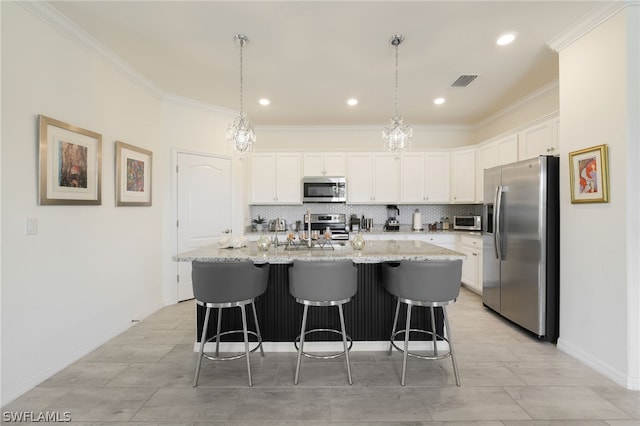 kitchen with white cabinets, appliances with stainless steel finishes, pendant lighting, and an island with sink