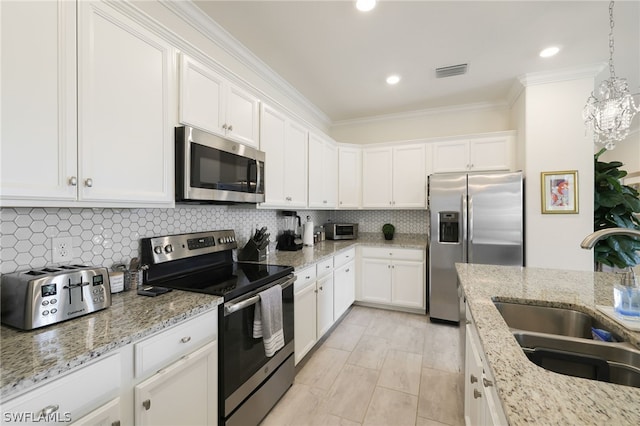 kitchen with appliances with stainless steel finishes, hanging light fixtures, sink, white cabinetry, and tasteful backsplash