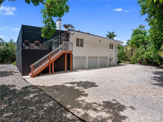 back of property with glass enclosure and a garage