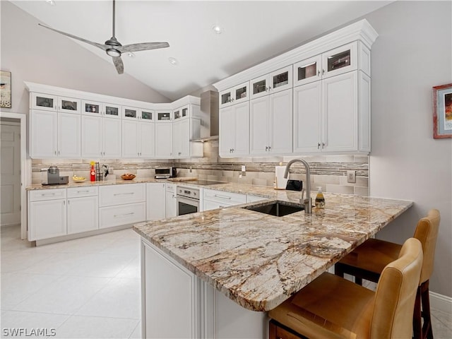 kitchen with sink, white cabinets, wall chimney range hood, and vaulted ceiling