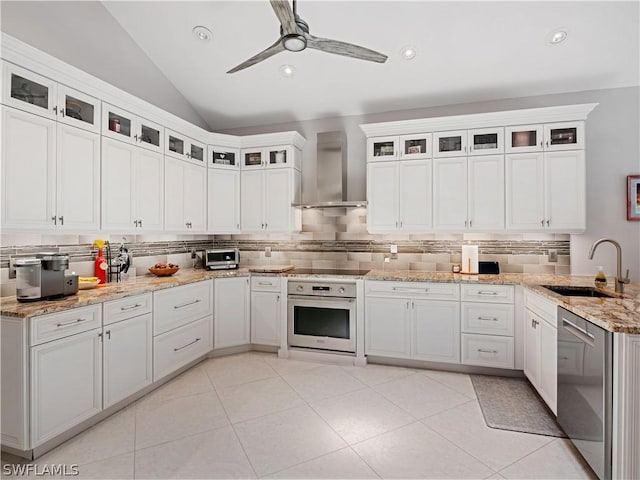 kitchen with dishwasher, vaulted ceiling, wall chimney range hood, oven, and sink