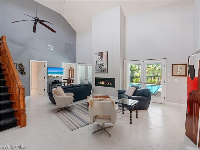 tiled living room featuring ceiling fan, french doors, and a towering ceiling