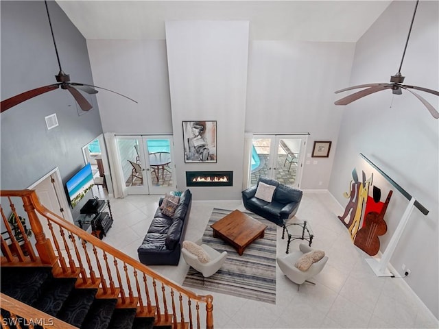 living room featuring a towering ceiling, french doors, and plenty of natural light