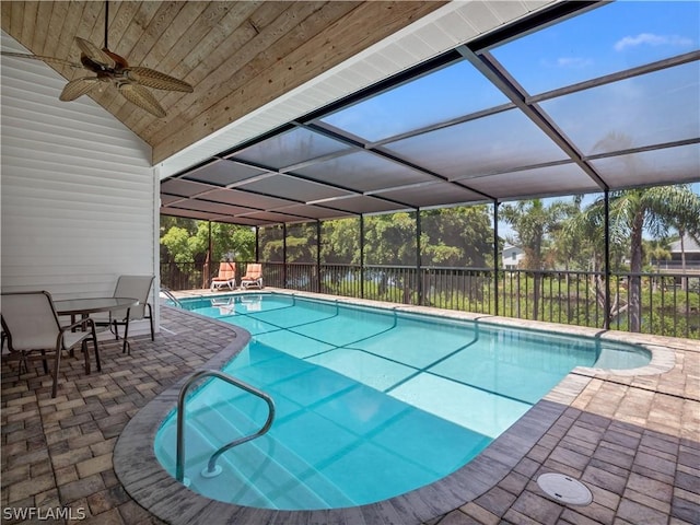 view of swimming pool with a patio area, ceiling fan, and glass enclosure