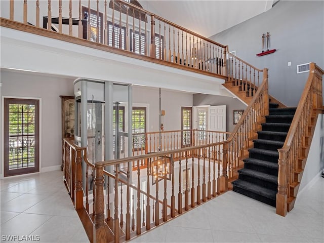 staircase with a towering ceiling, tile patterned flooring, and a chandelier