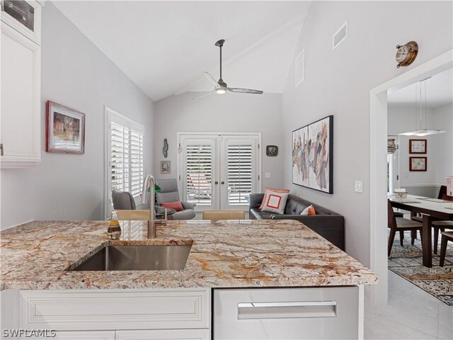 kitchen with sink, white cabinets, vaulted ceiling, french doors, and ceiling fan