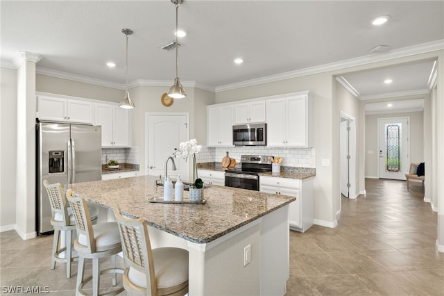 kitchen with stone counters, stainless steel appliances, white cabinetry, and a center island with sink