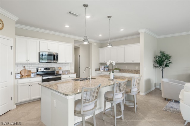 kitchen featuring stainless steel appliances, sink, decorative light fixtures, white cabinetry, and an island with sink