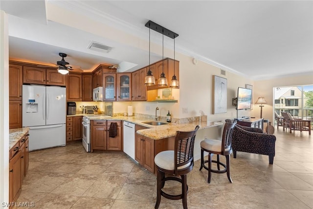 kitchen with sink, white appliances, kitchen peninsula, hanging light fixtures, and crown molding