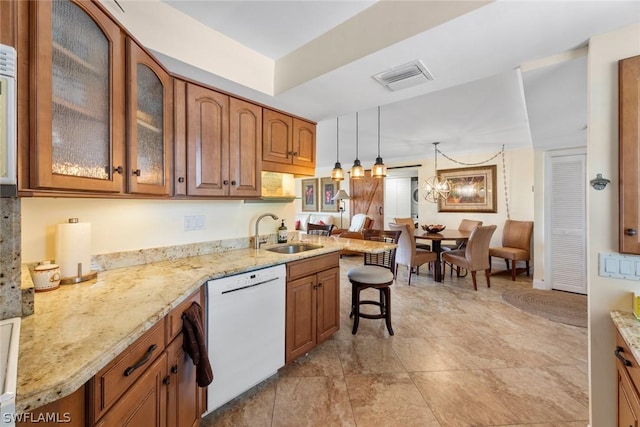 kitchen featuring a kitchen breakfast bar, kitchen peninsula, white dishwasher, sink, and decorative light fixtures