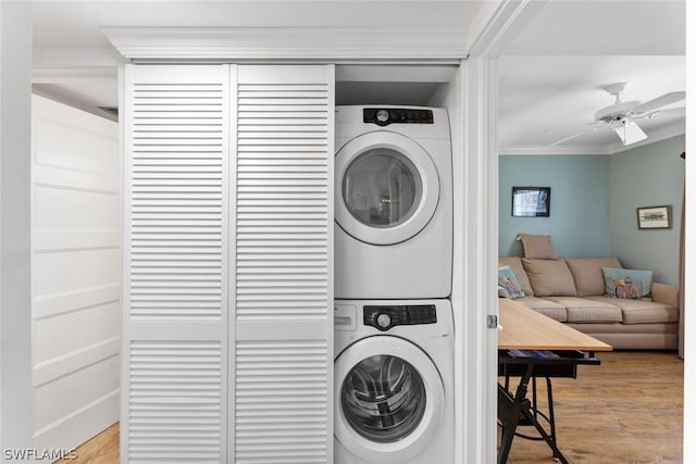 laundry area with stacked washing maching and dryer, ceiling fan, light hardwood / wood-style floors, and crown molding