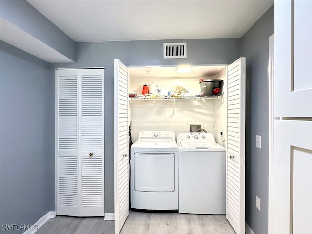 clothes washing area with independent washer and dryer and light hardwood / wood-style floors