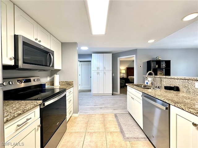 kitchen with appliances with stainless steel finishes, light stone countertops, and white cabinets