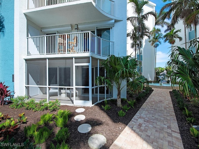 view of home's exterior with a sunroom and stucco siding