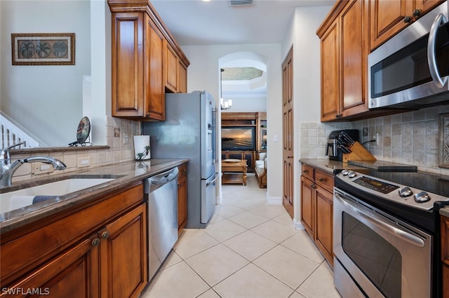 kitchen with backsplash, sink, light tile patterned floors, and stainless steel appliances