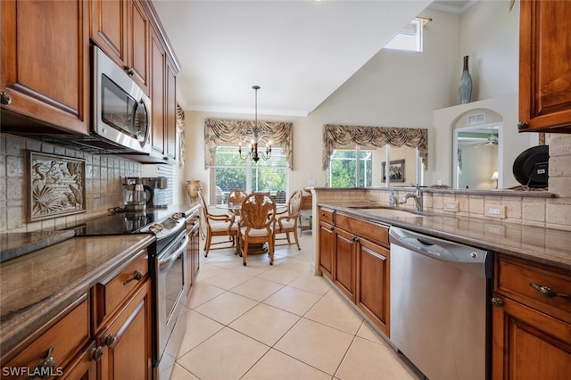 kitchen with pendant lighting, dark stone counters, sink, light tile patterned floors, and stainless steel appliances