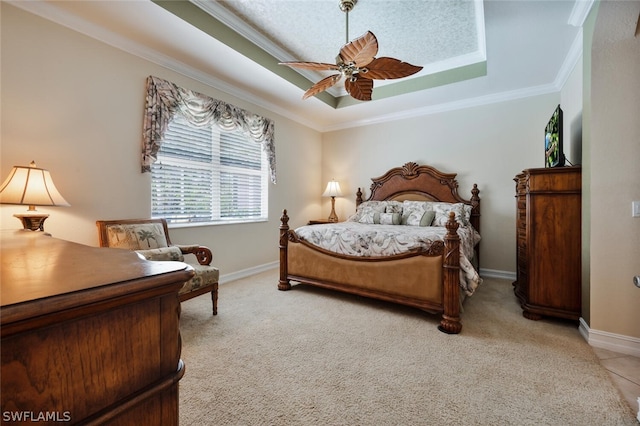 carpeted bedroom featuring a tray ceiling, ceiling fan, and crown molding