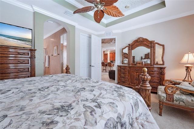 carpeted bedroom with ceiling fan, ornamental molding, and a tray ceiling