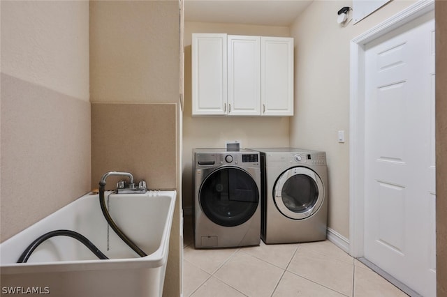 laundry area featuring washer and clothes dryer, cabinets, light tile patterned floors, and sink