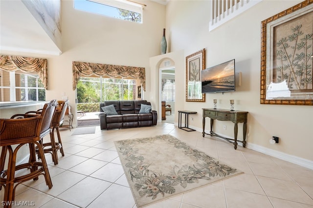 living room with a towering ceiling and light tile patterned floors