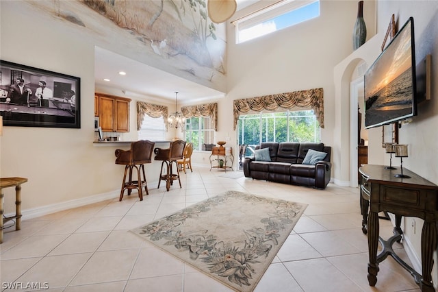 living room featuring light tile patterned floors, a towering ceiling, and a notable chandelier